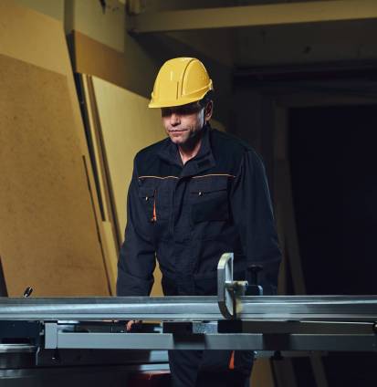 The woodworker is leaning at the wooden table.